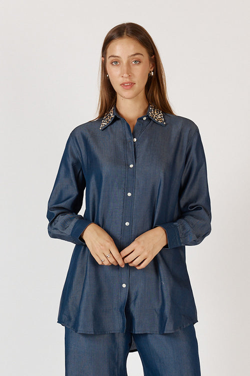 Front view of a model wearing the Rubyyaya Jonson Shirt, a denim collared cotton shirt with diamanté collar detail, shoulder yoke, and full-length adjustable sleeves, styled casually. Model is 5'9".